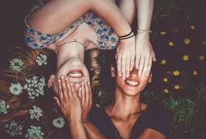 man and woman smiling while laying on lawn field