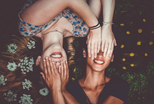 man and woman smiling while laying on lawn field