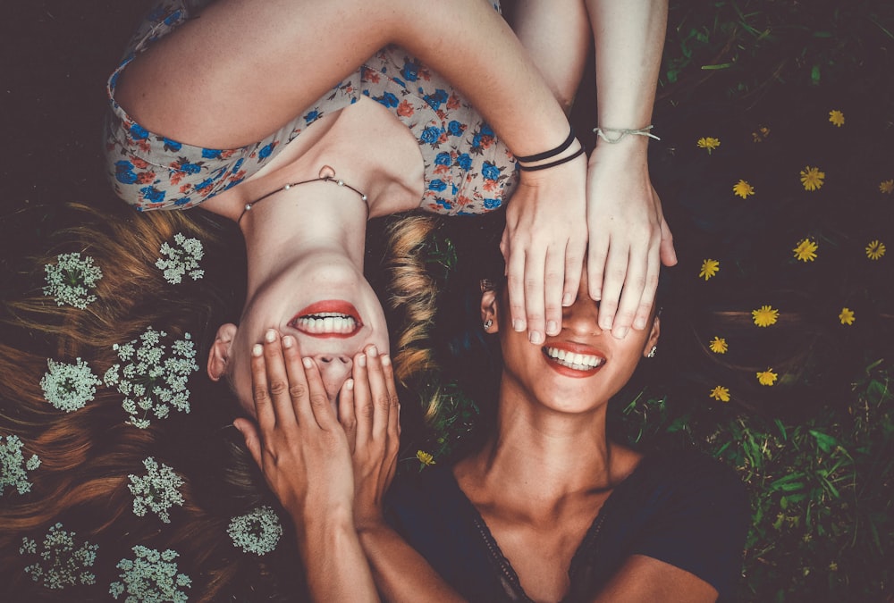 man and woman smiling while laying on lawn field