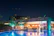 Guests enjoying a serene meal by the illuminated swimming pool at dusk.