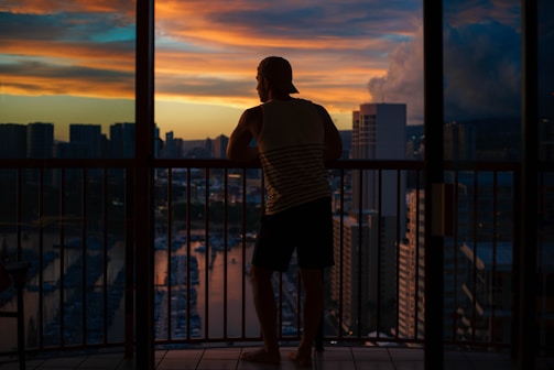 Modern city apartment balcony overlooking skyline at sunset.