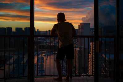 Bright apartment balcony overlooking city skyline at sunset.