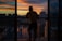 A smiling woman enjoying her balcony view overlooking the city skyline at sunset.