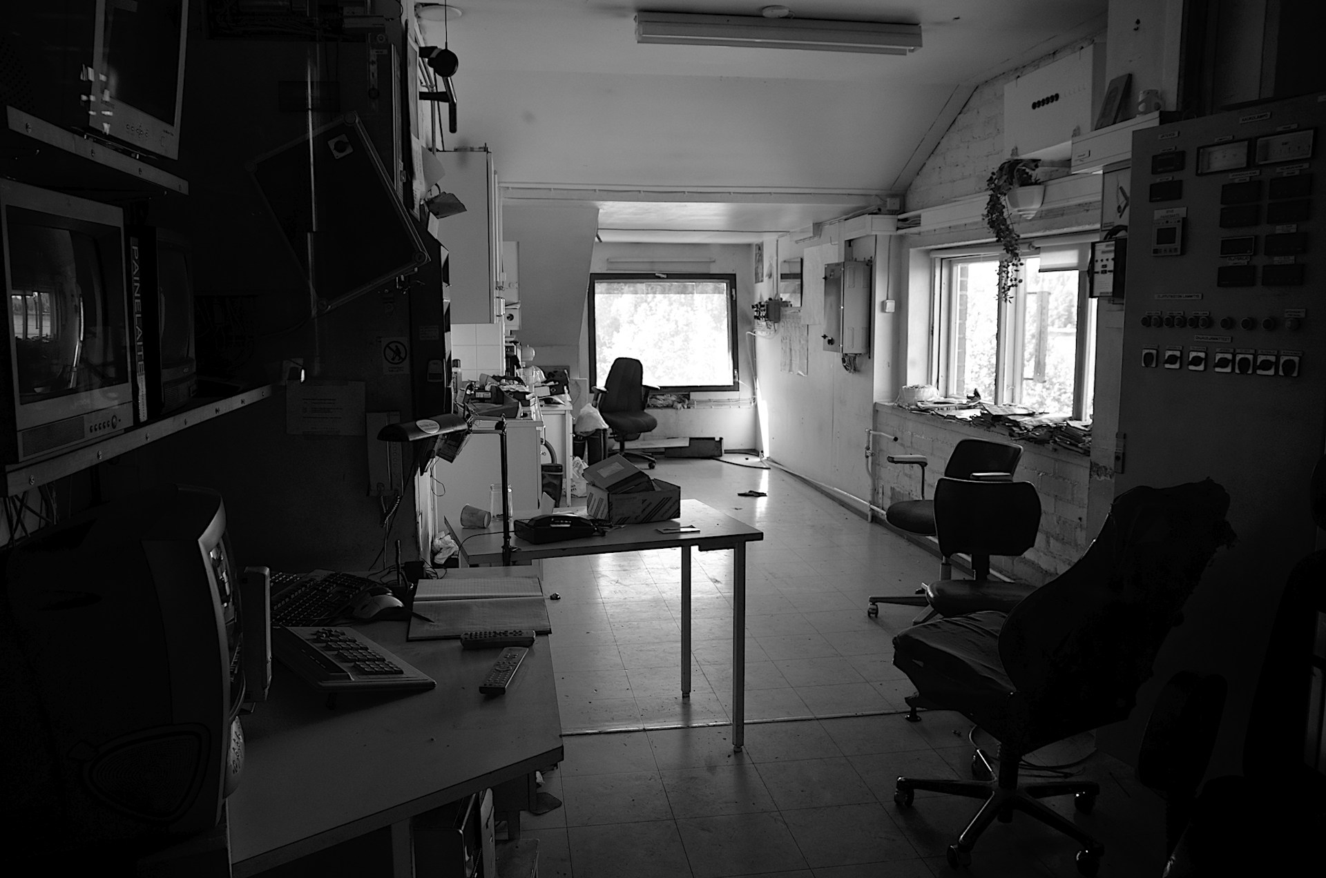 A shadowy lab filled with obsolete machines and magnetic tape reels, illuminated by the soft glow of retro-futuristic monitors.