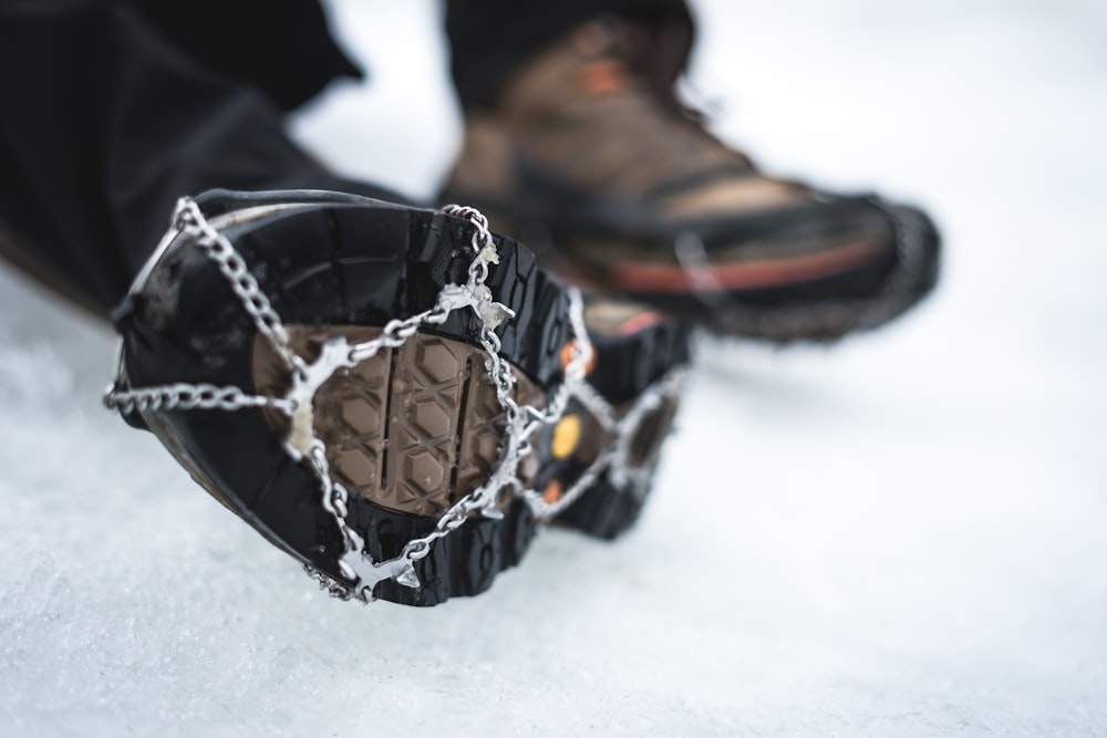 Fotografía de enfoque selectivo de bota negra con cadena de nieve