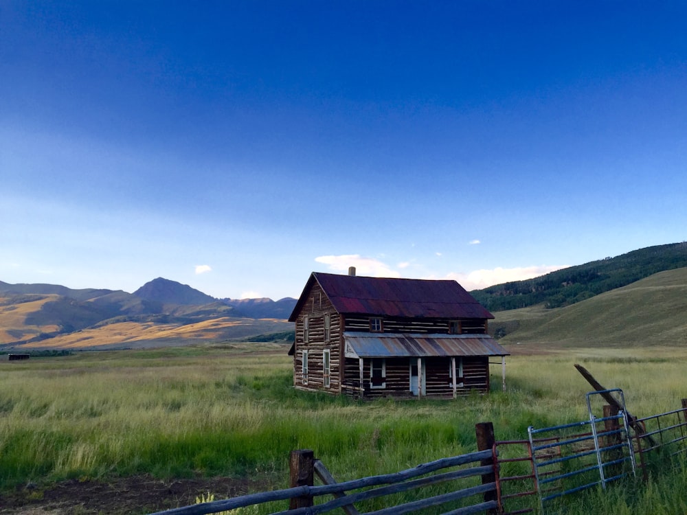 red barn near hill under blue sky during daytime