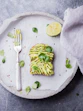 wheat bread with avocado spread beside white plastic spoon and pressed lime on round white plate