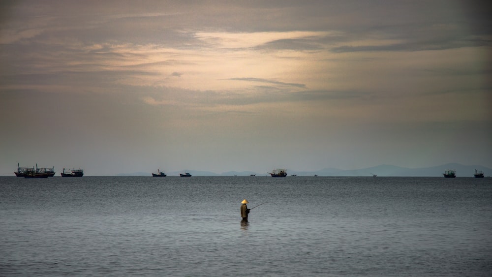 person fishing in the middle of body of water