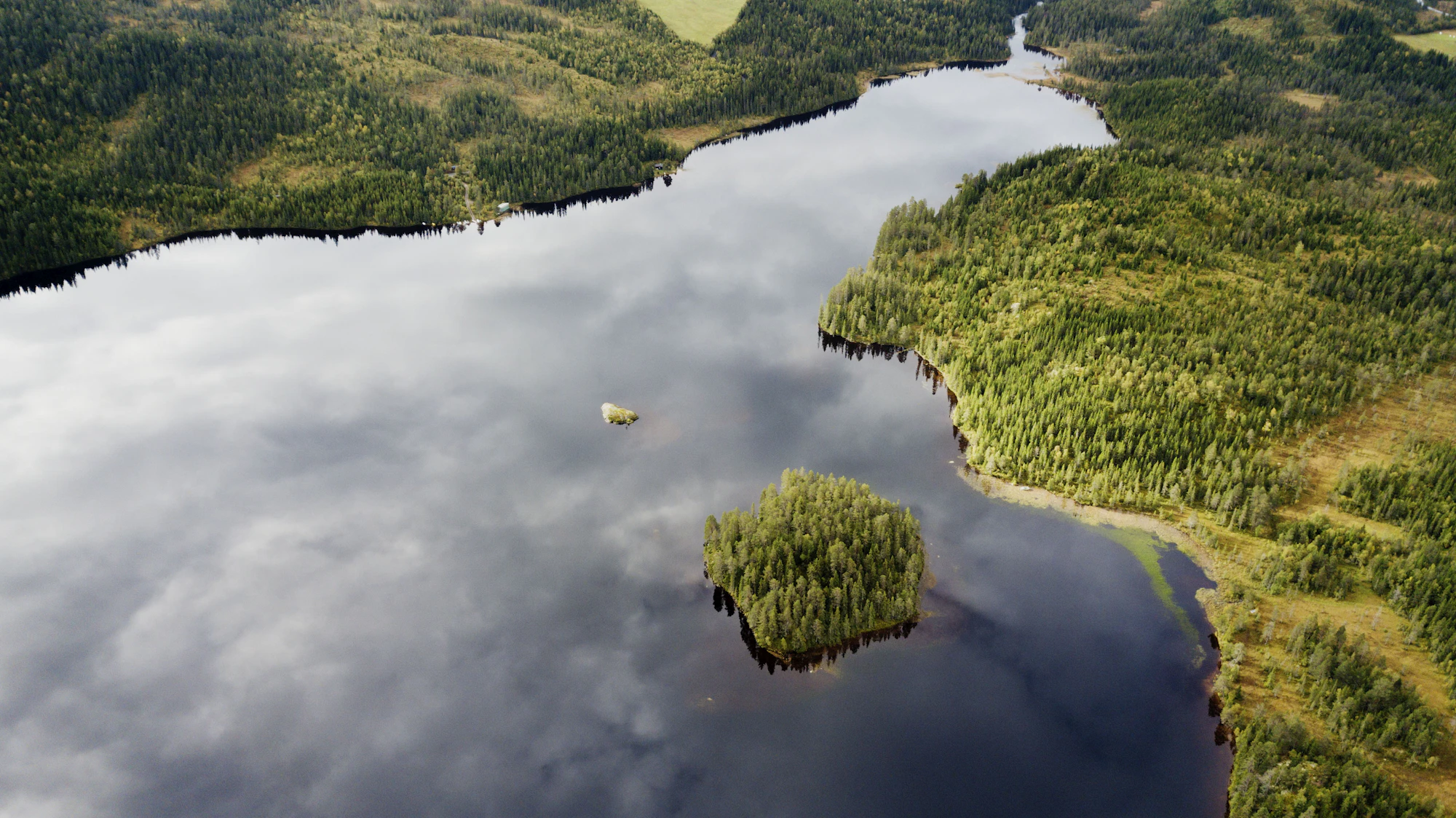 Et lite fjelltjern sett ovenfra, med skyene speilet i vannet