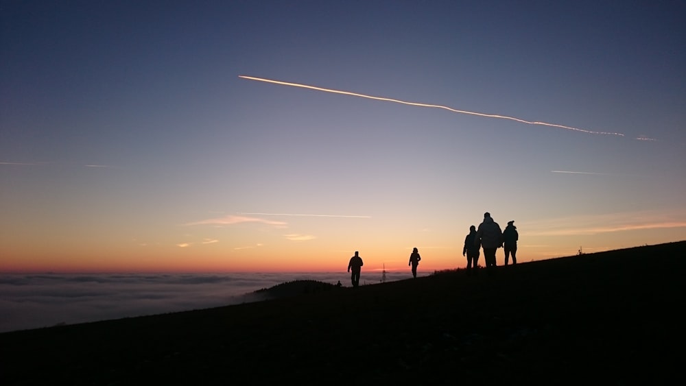 夕暮れ時に山を歩く5人のグループのシルエット写真