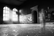 grayscale photo of person standing inside building
