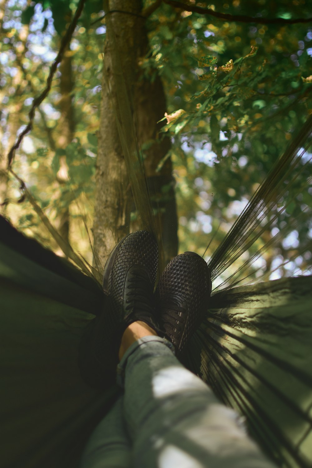 Person auf Camping-Hängematte an Baum gebunden