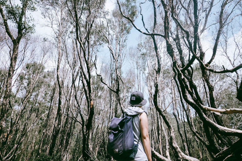 man carrying black backpack surrounded by trees at daytime