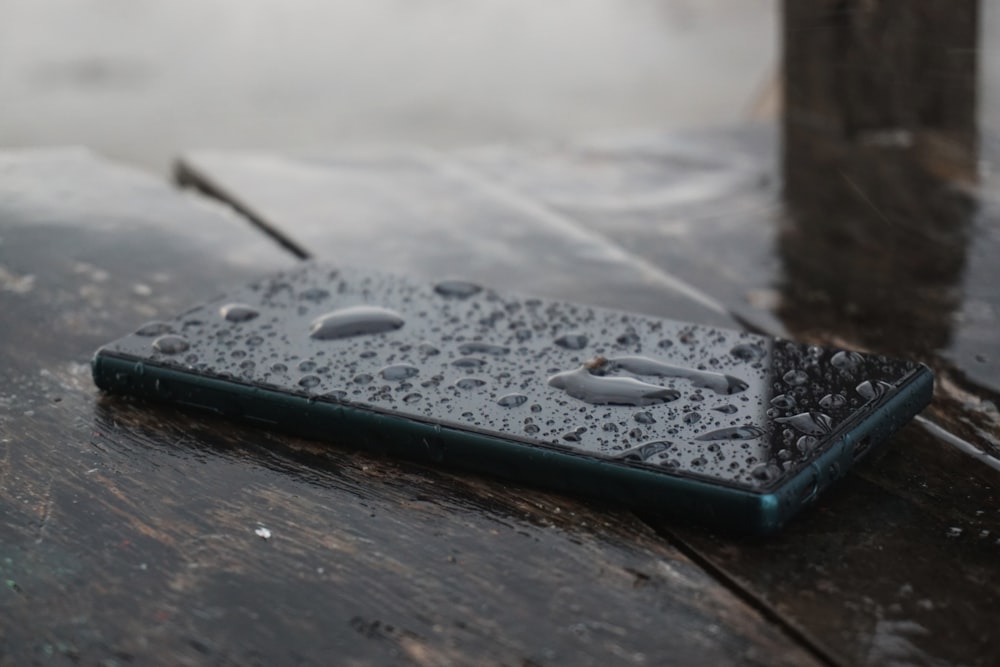 black smartphone on top of brown wooden surface