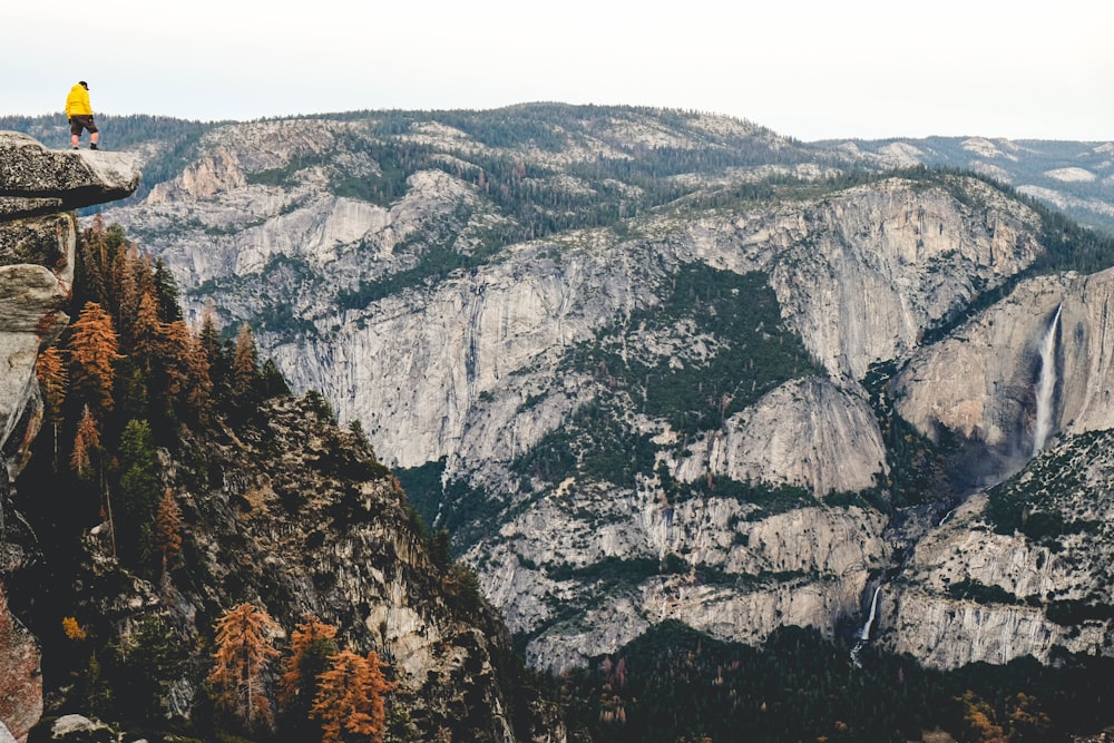 person standing on cliff under cloudy skies