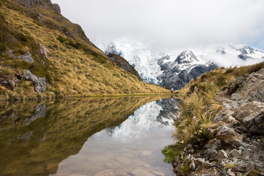 body of water in the middle of mountains during daytime in Mount Cook New Zealand