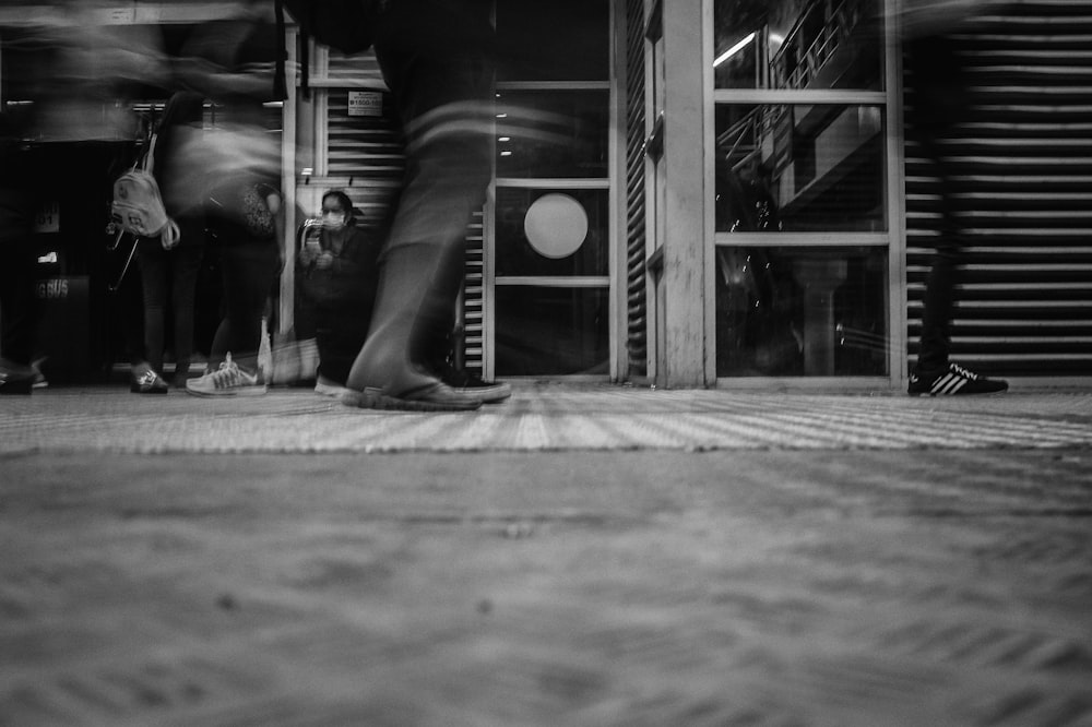 a black and white photo of people walking in front of a store