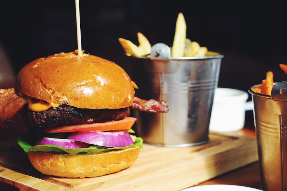 hamburger near gray stainless steel bucket filled with potato fries