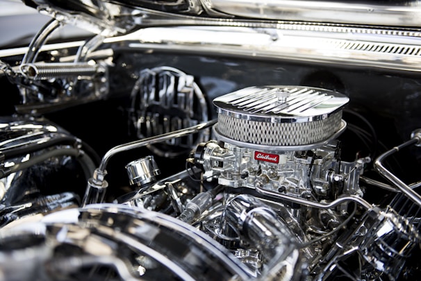 Close-up of a high-performance Holley carburetor gleaming under bright workshop lights