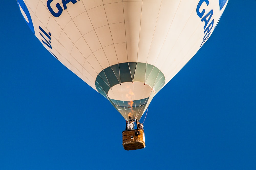 person inside brown, white, and green hot air balloon low angle photography