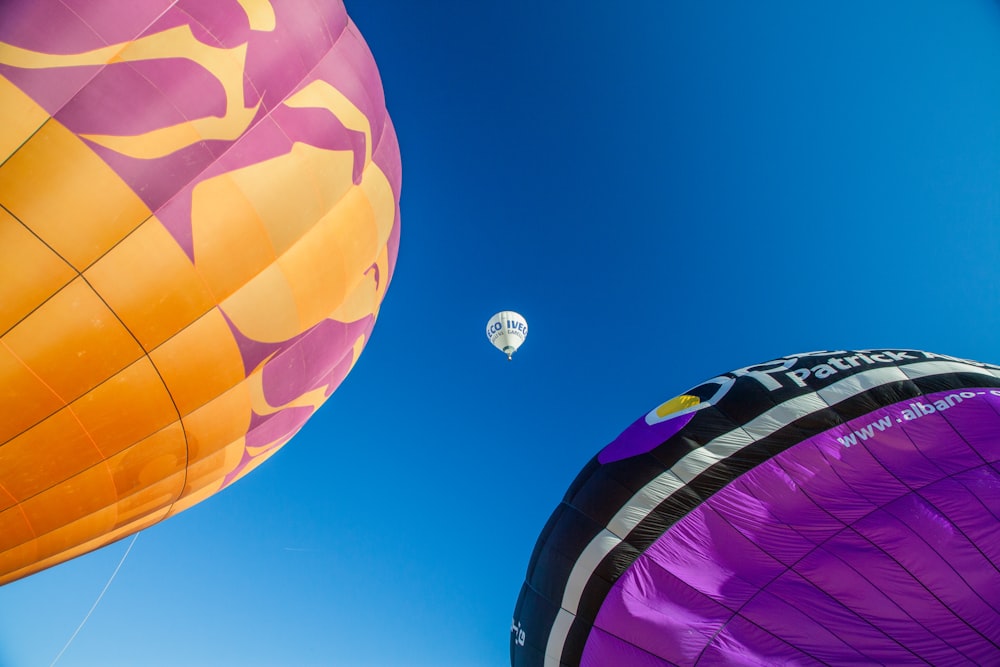 Drei verschiedenfarbige Heißluftballons unter blauem Himmel