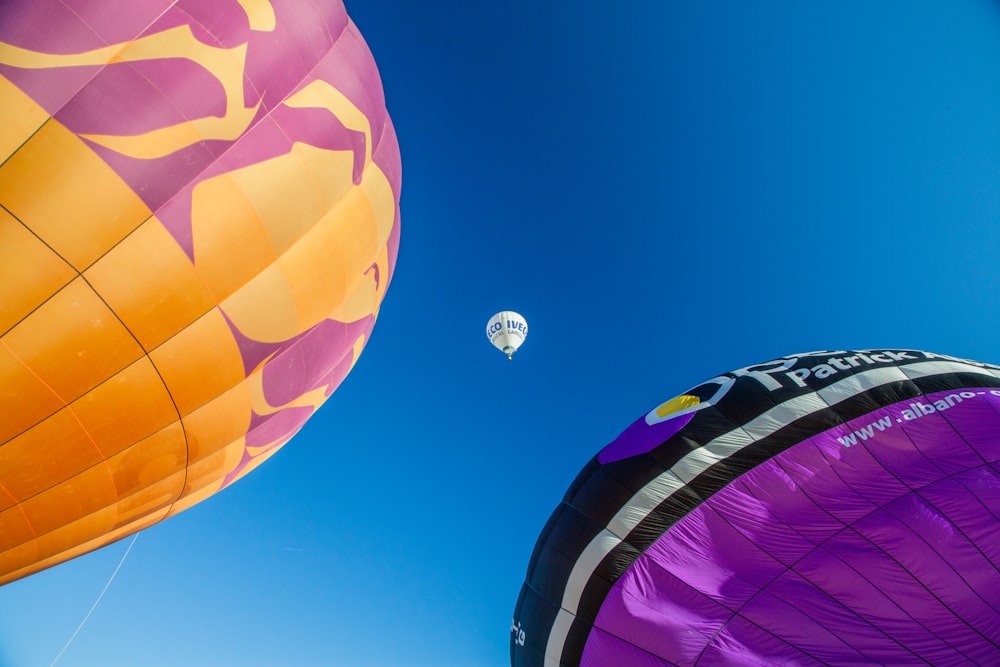 Tre mongolfiere di colori assortiti sotto il cielo blu