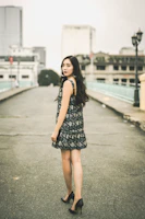 A sophisticated woman in a flowing golden dress walking through a minimalist urban setting.