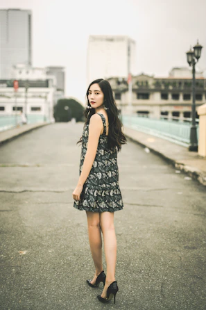 A sophisticated woman in a flowing golden dress walking through a minimalist urban setting.