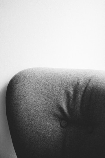 Close-up shot of a charcoal flannel shirt draped over a sleek black leather chair, highlighting fabric texture and stitching.