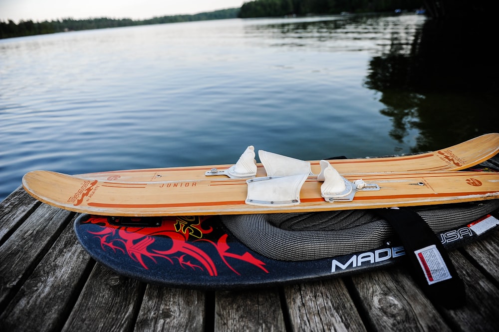 brown water ski on gray wooden dock near body of water