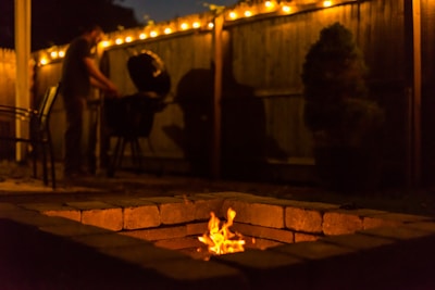 Evening shot of a lit barndominium showing cozy outdoor seating and fire pit.