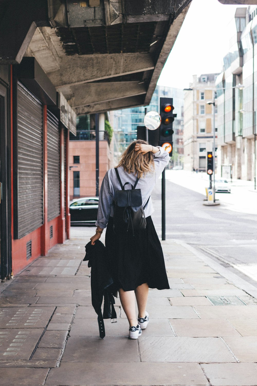 woman wearing gray dress shirt with black skirt and black backpack