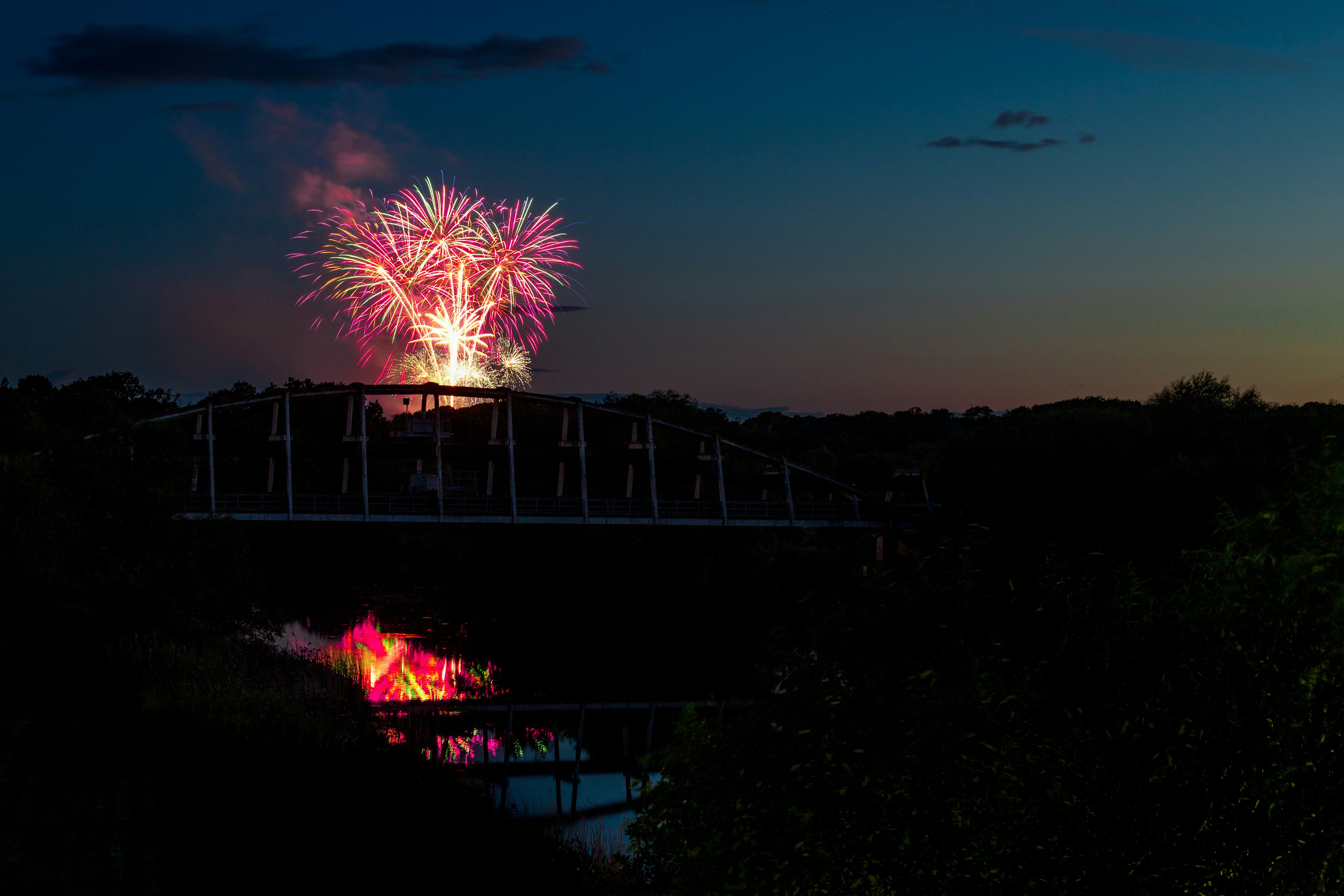 silhouette photo of suspension bridge in front of fireworks