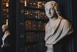 man wearing robe bust figurine near black wall