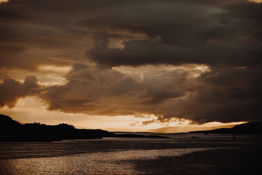 grey calm body of water under nimbus clouds