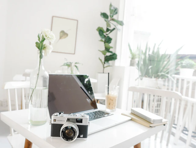 A sleek, minimalist workspace with a laptop, coffee cup, and soft natural light highlighting a creative vibe.
