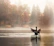 Close-up of a duck in flight over calm, misty marsh waters at dawn.
