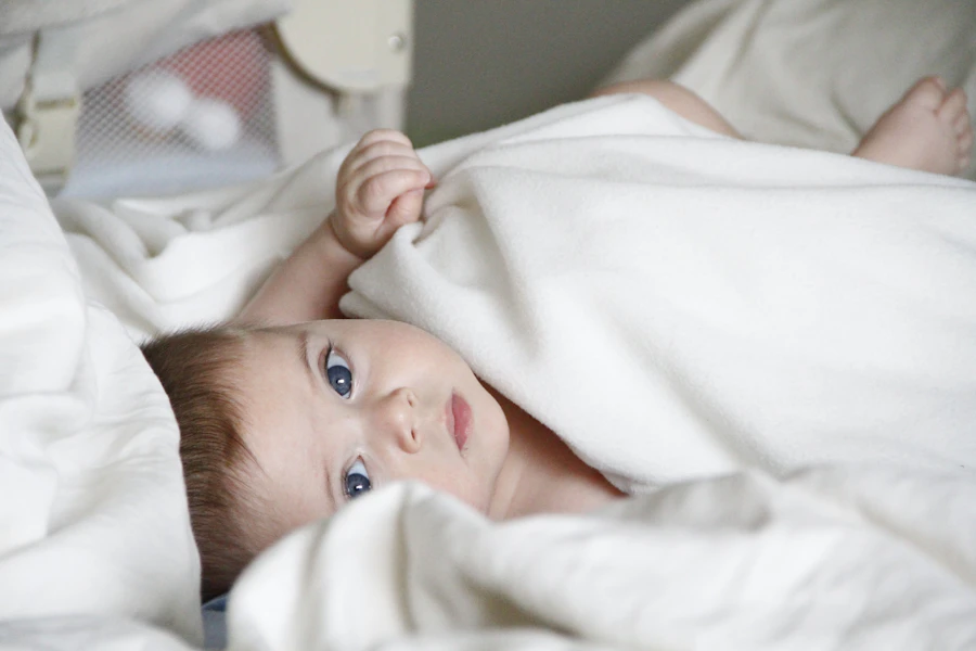 Newborn resting in soft natural light with gentle baby clothing nearby