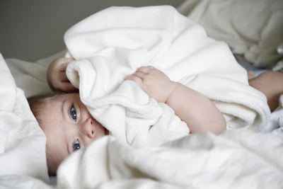 A joyful baby wrapped in a cozy blanket, eyes wide with wonder in a softly lit nursery.