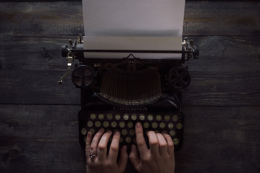 person holding white and black typewriter