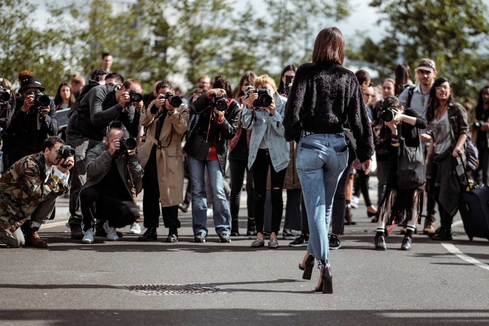 woman walking taking photo by people