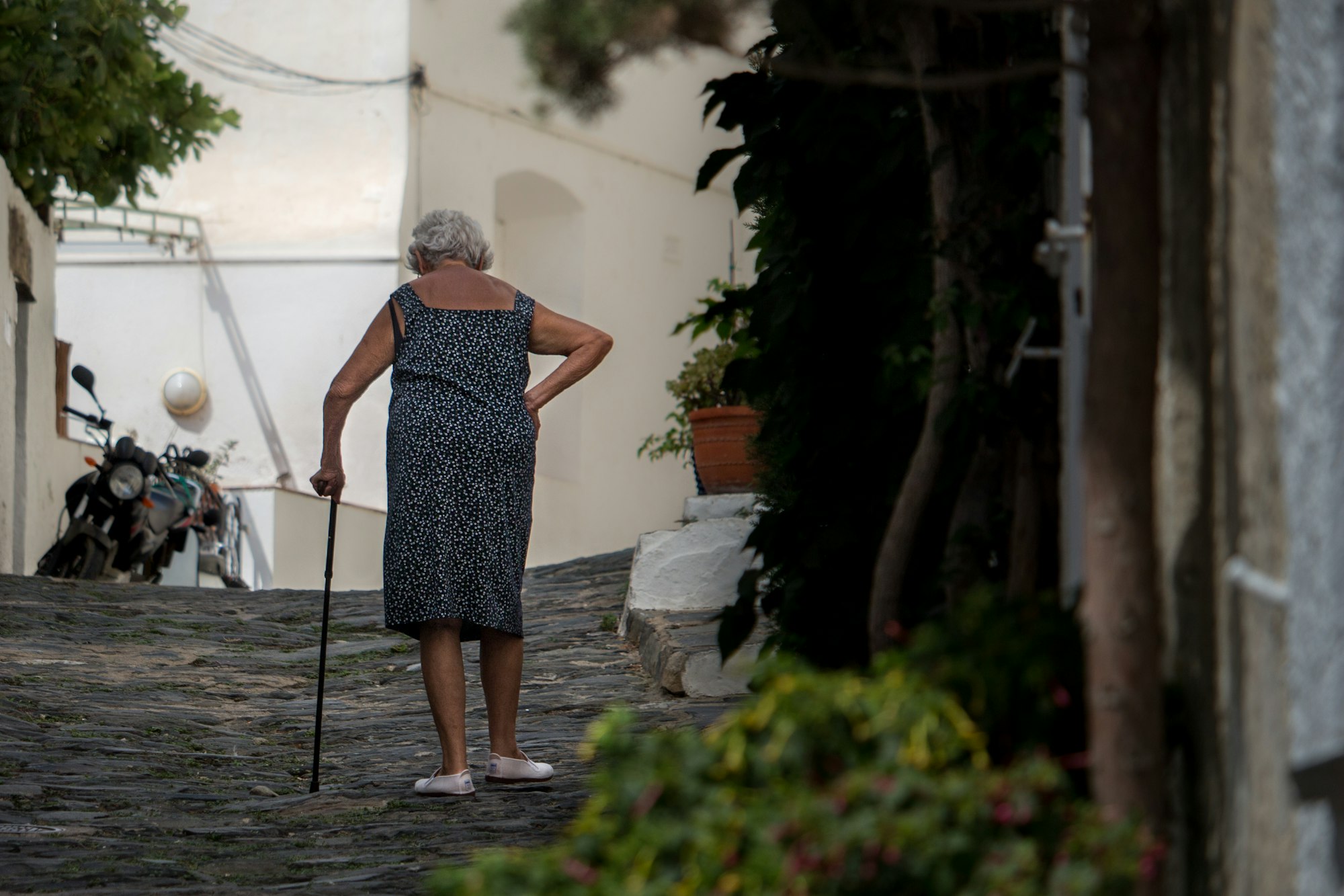 An old woman using a crane to walk