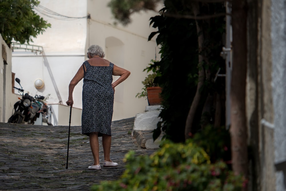 woman walking while holding cane near tall tree