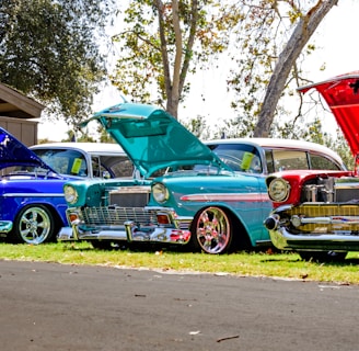 three red, blue, and teal classic cars