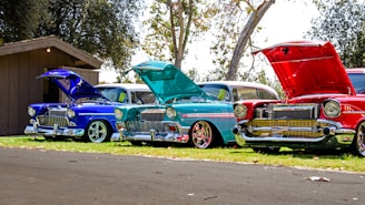 three red, blue, and teal classic cars