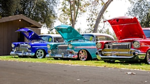 three red, blue, and teal classic cars
