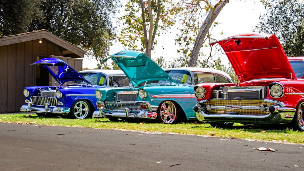 three red, blue, and teal classic cars