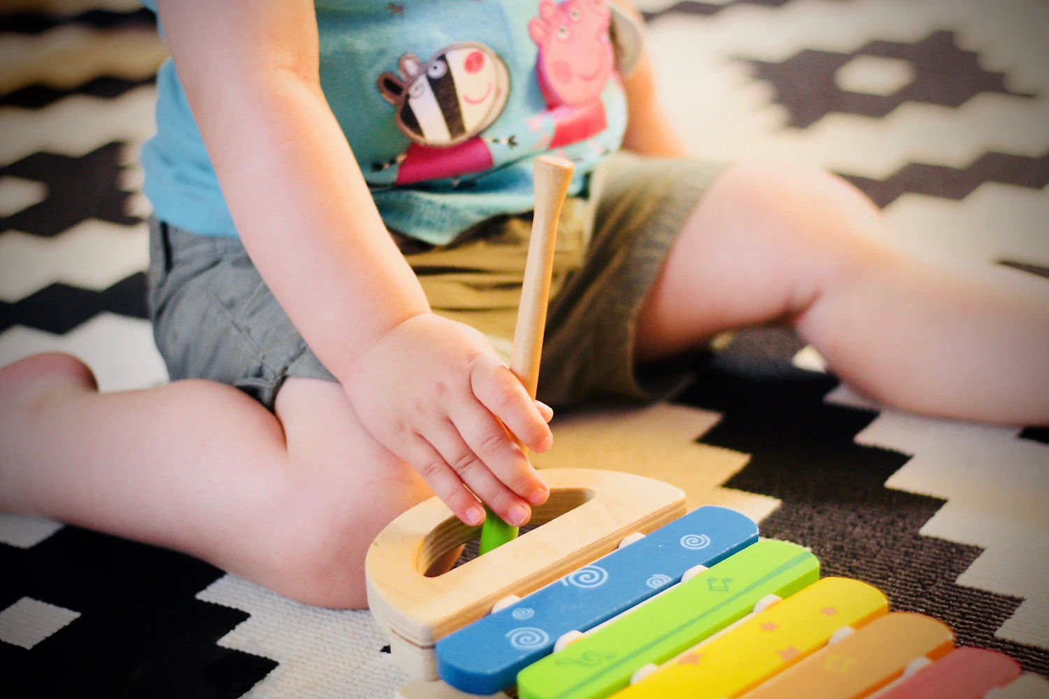 A young child deeply focused on playing on the carpet, right before a transition