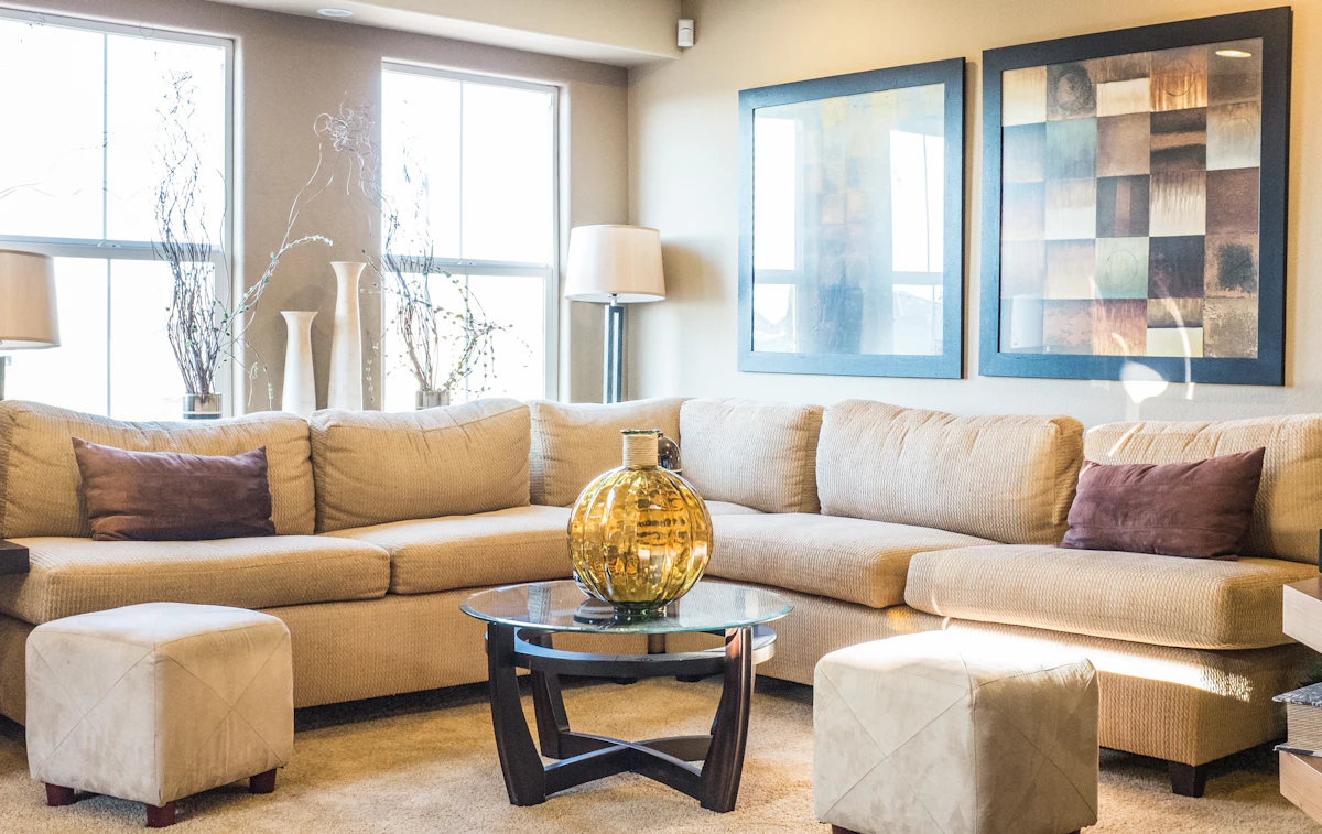 Wraparound beige sectional with ottomans and a glass coffee table