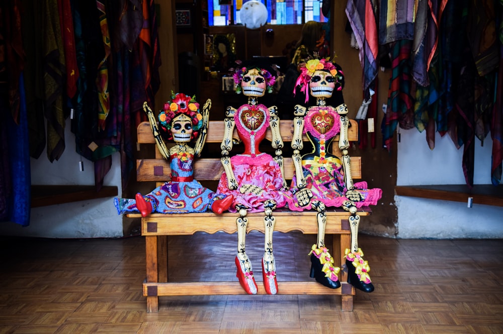 três bonecas de esqueleto de Frida Kahlo sentadas no banco